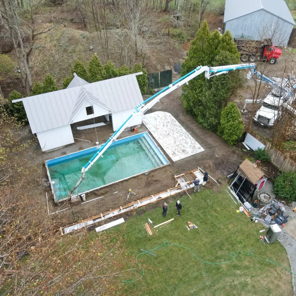 Aerial view of a residential backyard with workers from Hines Ground Services using a concrete pump to pour concrete into a large home foundation.
