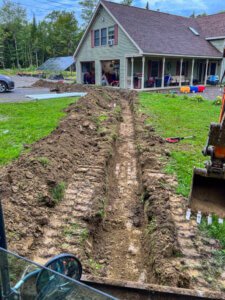 A trench is being dug in front of a house.