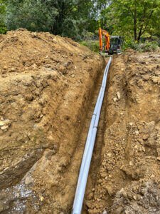 A large pipe is being installed in a dirt field.