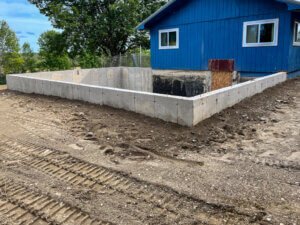 A concrete foundation is being built in front of a house.