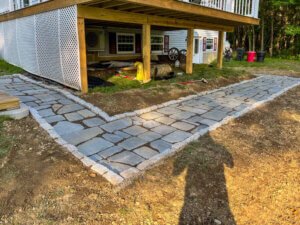 A stone walkway with a wooden deck in front of a house.