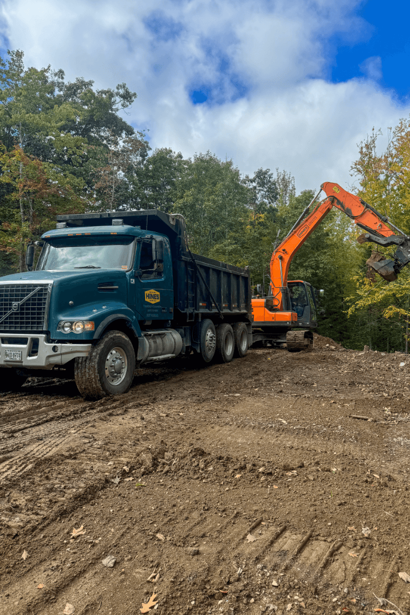 Photo of a dump truck with the Hines logo and an excavator