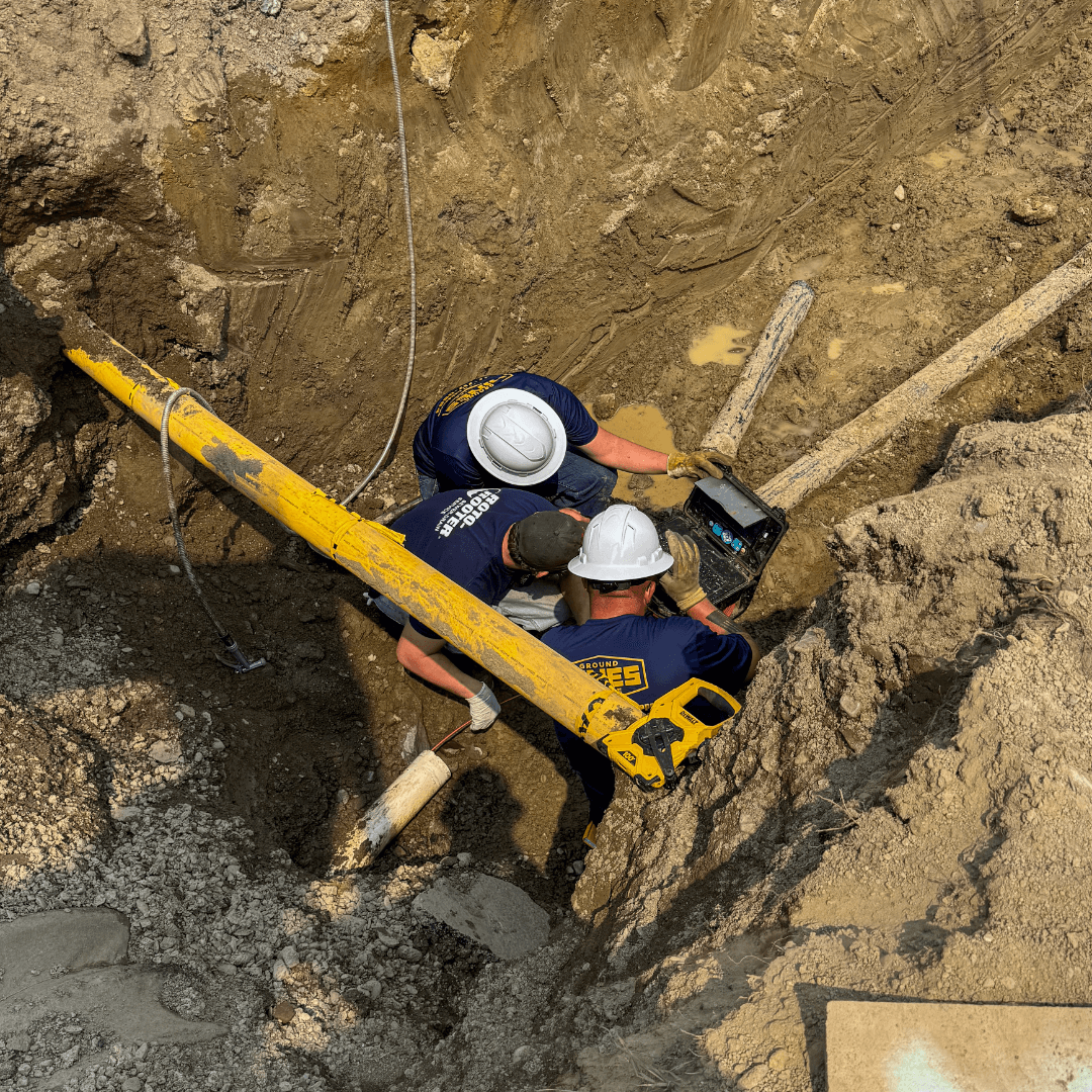 Photo of Hines workers in hard hats working in a muddy ditch